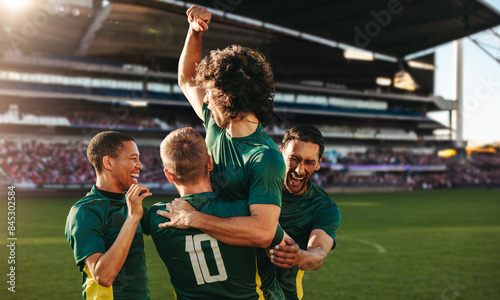 Football players celebrating victory in a professional football match at a full big stadium photo