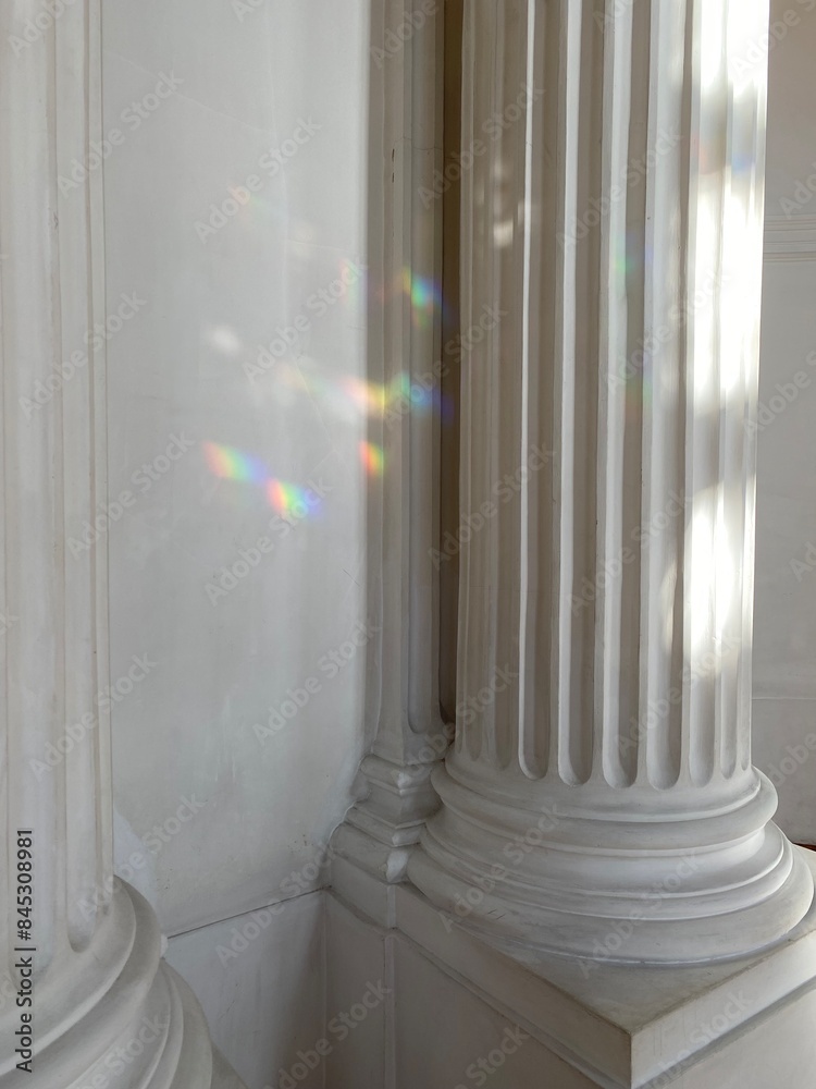 Aristocratic aesthetics of classic white columns with flutes. Refractions of light are visible on the columns, creating multicolored highlights. Aristocratic aesthetics of classic white columns with flutes. Refractions of light are visible on the columns, creating multicolored highlights.