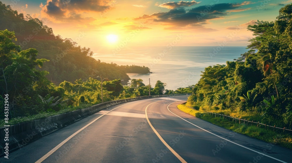 Empty highway, dense tropical forest on one side of the road and sea coast on the other, , sky illuminated by the sun's rays at sunset, incredible nature Empty highway, dense tropical forest on one side of the road and sea coast on the other, , sky illuminated by the sun's rays at sunset, incredible nature