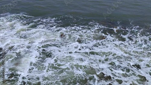 Small sea water waves hitting to brown stones, daylight, full HD photo