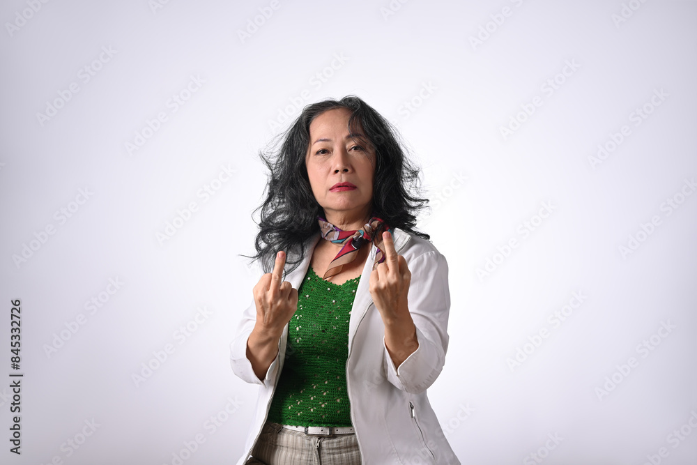 Portrait of senior woman showing middle finger gesture against white background