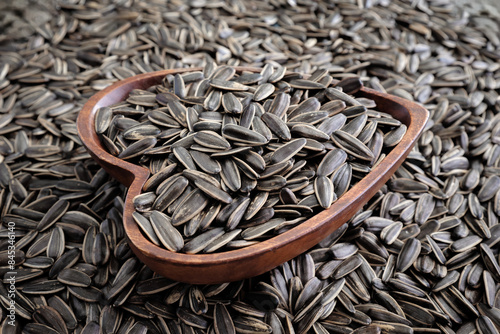 Close-up a heart shaped wooden bowl with striped sunflower seeds.