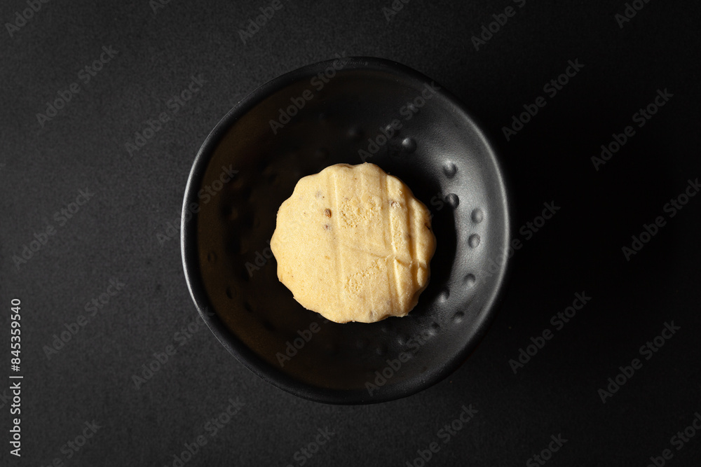 Carrom seed cookies or salted ajwain cookies are placed in a black bowl on a black background. Carrom seed cookies or salted ajwain cookies are placed in a black bowl on a black background.