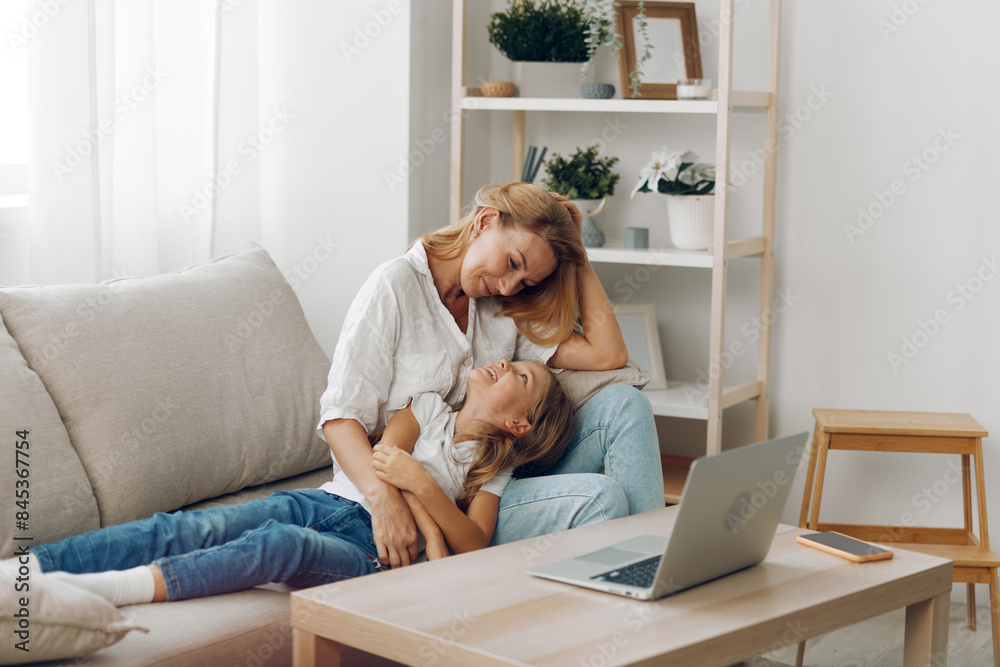 Mother and child bonding on a cozy couch, exploring educational content on a laptop with a bookshelf backdrop