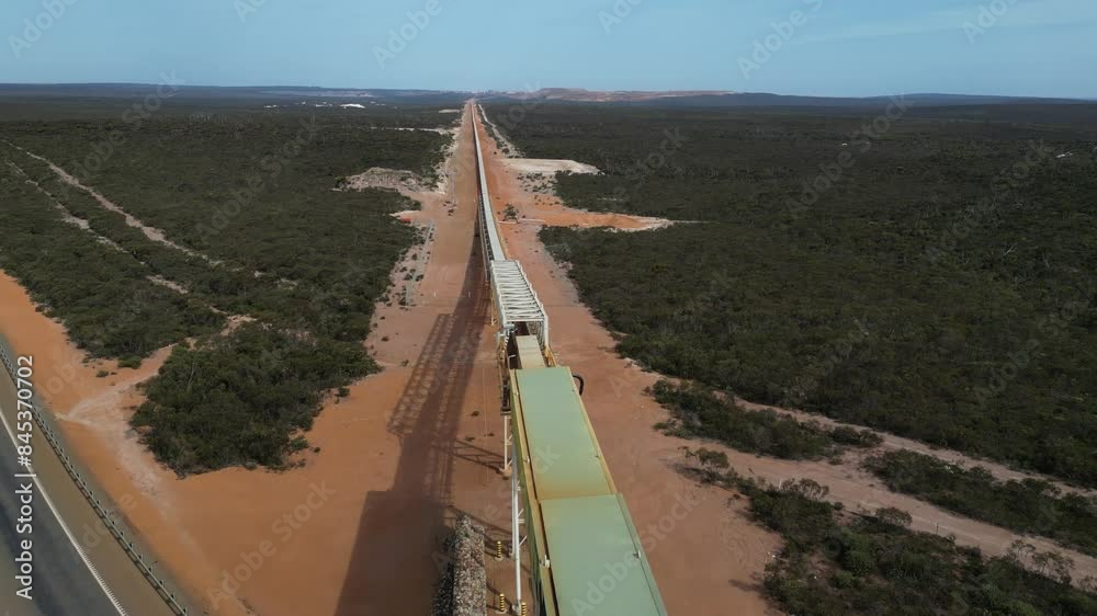 Very long mining conveyor belt system passing over road, Western Australia. Aerial tilt-down forward Very long mining conveyor belt system passing over road, Western Australia. Aerial tilt-down forward