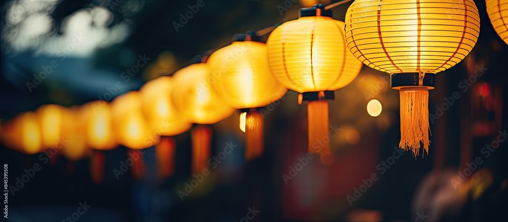 A row of yellow lanterns at night against a blurred background The subject is out of focus. Creative banner. Copyspace image A row of yellow lanterns at night against a blurred background The subject is out of focus. Creative banner. Copyspace image