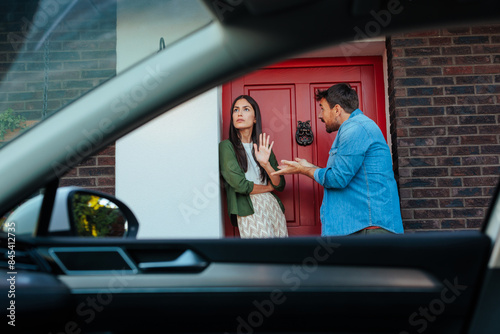 Couple gesturing at a red door entrance