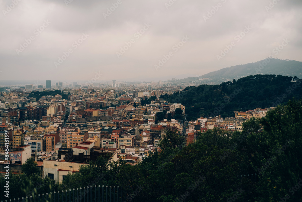 A panoramic view captures an urban cityscape nestled between mountains, dense buildings under a cloudy sky A panoramic view captures an urban cityscape nestled between mountains, dense buildings under a cloudy sky
