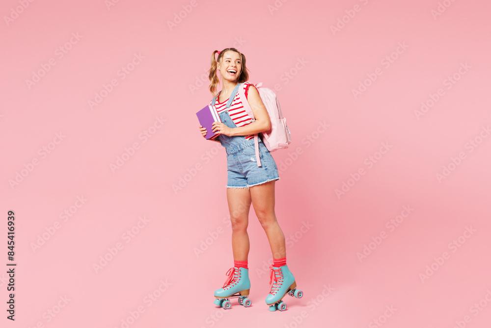 Young smiling girl student wear casual clothes backpack bag rollers rollerblading hold books look aside isolated on plain pink background. Summer sport leisure, high school university college concept. Young smiling girl student wear casual clothes backpack bag rollers rollerblading hold books look aside isolated on plain pink background. Summer sport leisure, high school university college concept.