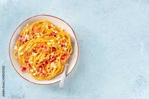 Carbonara pasta dish, traditional Italian spaghetti with pancetta and cheese, with a fork, overhead flat lay shot with copy space