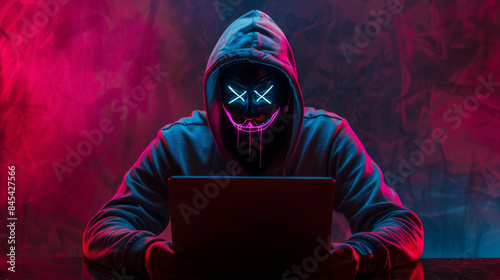 Hacker in a neon mask. Cyber criminal with laptop. Cyber crime, hacker activity, digital system security, cyber attack threat, malware virus alert concept, fraud money, ddos attack.