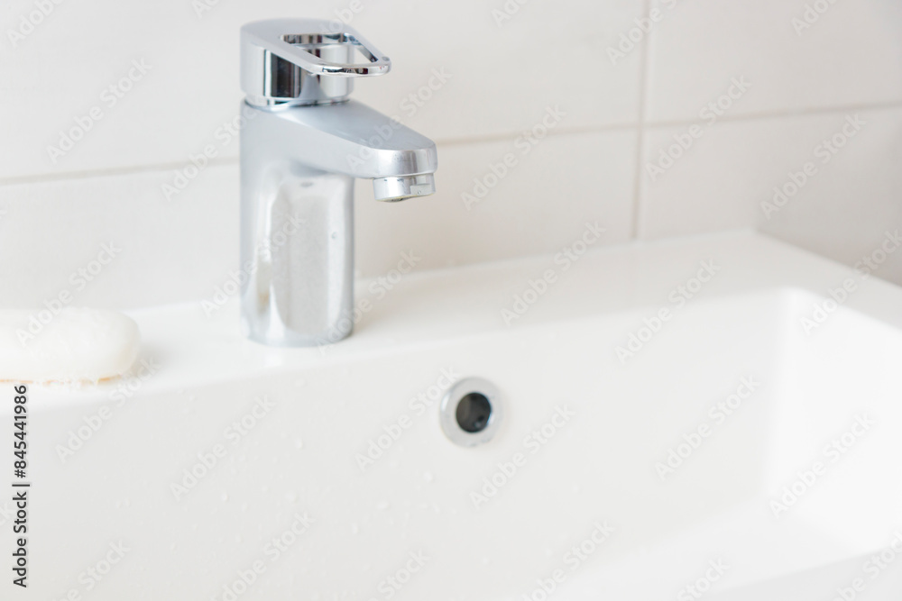 Modern bathroom chrome faucet, white tiles wall, water tap and sink, cleanness concept, close water, saving natural recourses concept banner with copy space Modern bathroom chrome faucet, white tiles wall, water tap and sink, cleanness concept, close water, saving natural recourses concept banner with copy space
