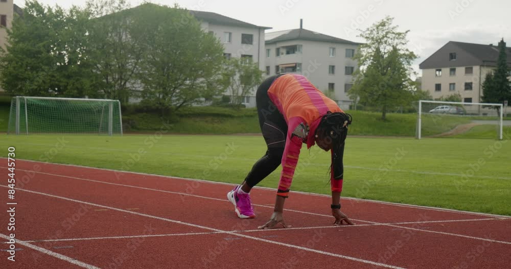 Female athlete ready to sprint on track field Female athlete ready to sprint on track field
