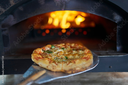 Homemade Pizza Margherita On Paddle Being Put Into Wood Burning Stove At Street Food Market