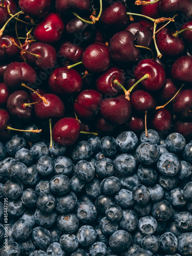 Mix of fresh ripe sweet cherry and blueberries background. Closeup, top view.