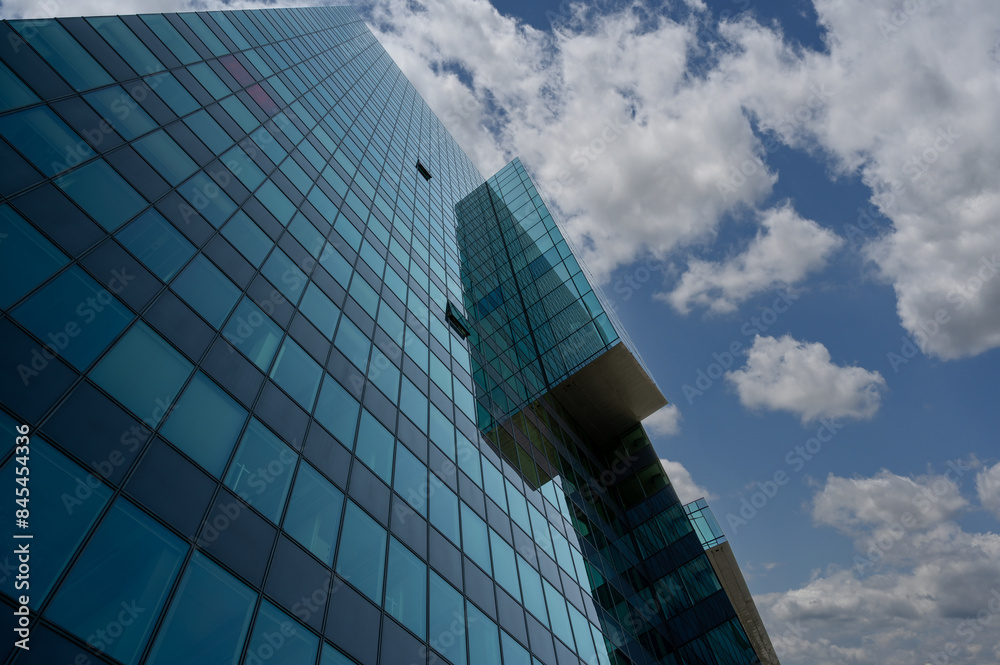 Obraz premium Vienna, Austria, August 17, 2022. Donau City is the city district characterized by modern skyscrapers, in the photo the detail of a glass facade. Play of reflections between the surfaces.
