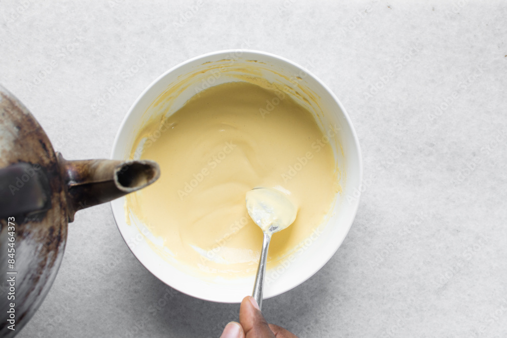 Overhead view of nigerian akamu being made in a white bowl, pap akamu or ogi in a white bowl, top view of nigerian corn pudding in a white ramekin