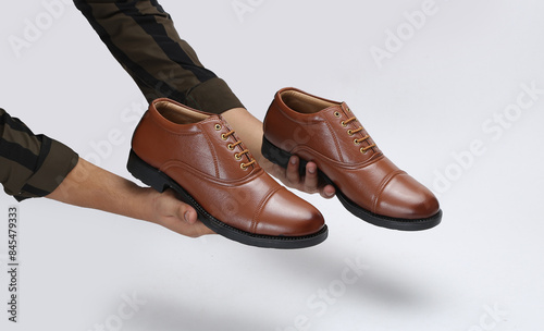 Wallpaper Mural Hand holding pair of modern leather shoes on white background Torontodigital.ca