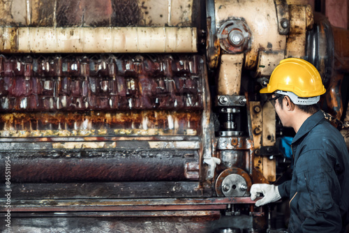 Asian engineer mechanic man checking and using wrench for maintenance pressing metal machine at factory, worker at industrial working photo