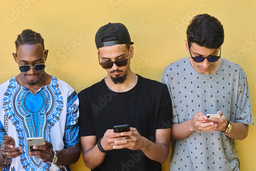 Diverse Teen Group Standing Together Against Wall Using Smartphones photo