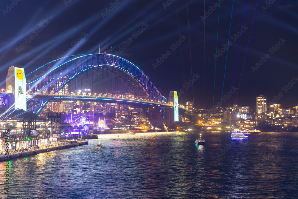 Obraz premium Colourful Light show at night on Sydney Harbour NSW Australia. The bridge illuminated with lasers and neon coloured lights Vivid Sydney Laser and Light Drone show