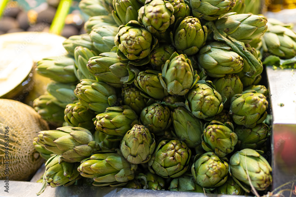 Fresh green artichokes in a market. Fruit and vegetable stand, view of artichokes. Counters with fresh vegetables