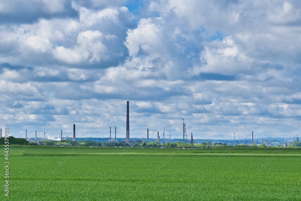 Large industry near a field with agricultural use, cloudy dramatic sky Large industry near a field with agricultural use, cloudy dramatic sky
