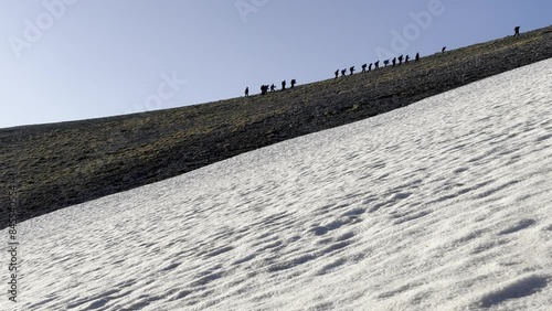 Sportive climbing activity of a large group of mountaineers towards the snowy mountains at the top photo