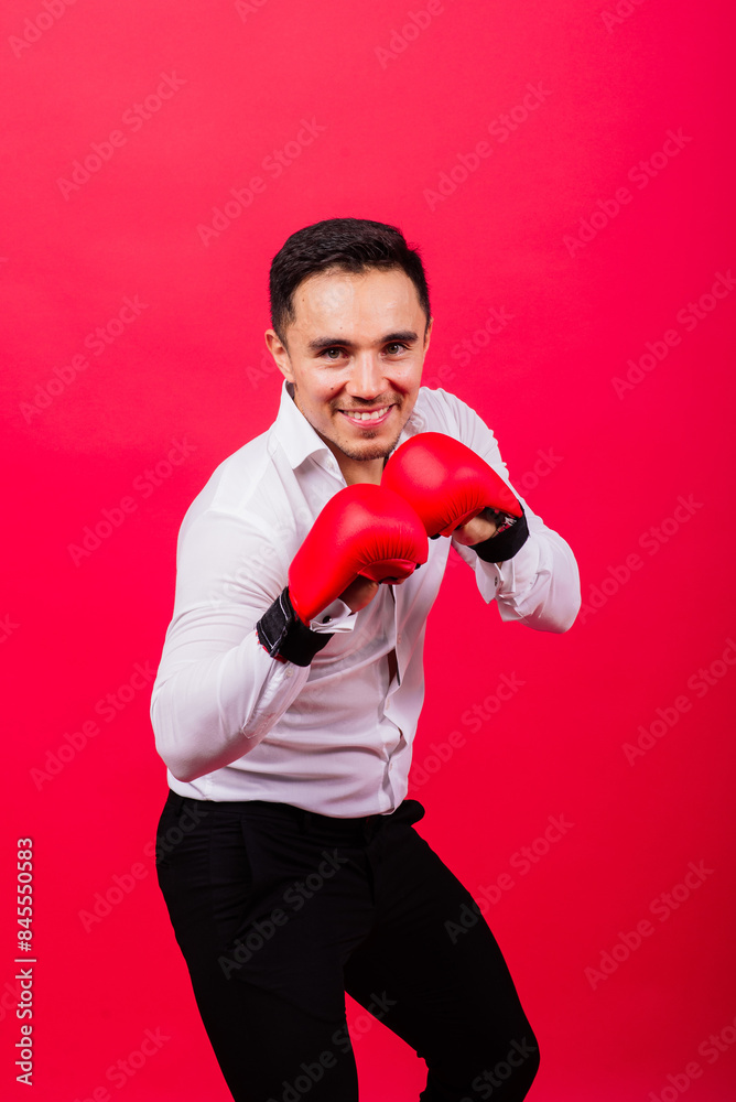 Handsome young businessman with boxing gloves. Studio red background