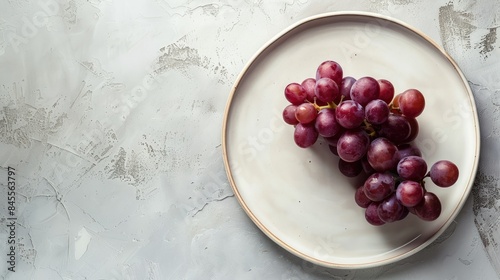 *A pristine white plate with a bunch of vibrant purple grapes, photographed with soft natural light