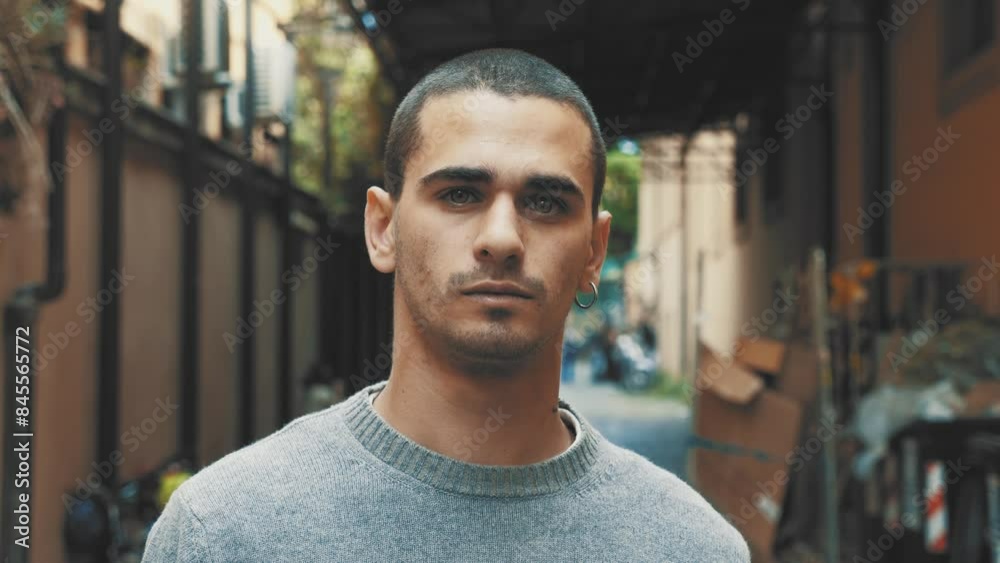 20-year-old man with short hair, wearing a gray sweater, standing in a suburban courtyard and looking seriously at the camera. 20-year-old man with short hair, wearing a gray sweater, standing in a suburban courtyard and looking seriously at the camera.