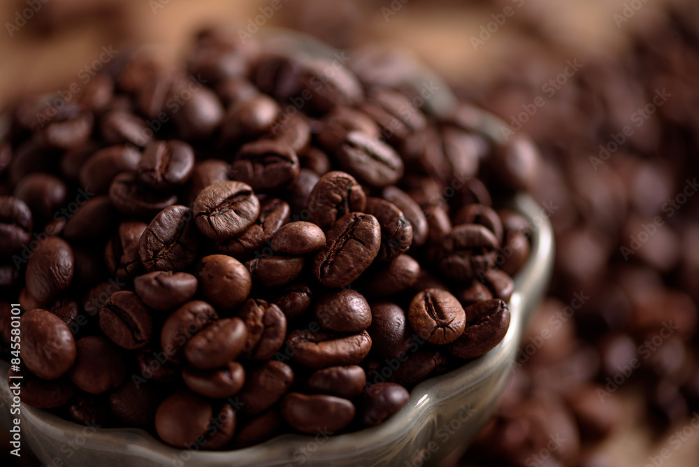 Fototapeta premium Coffee beans into bowl on white table. Top view. Soft focus