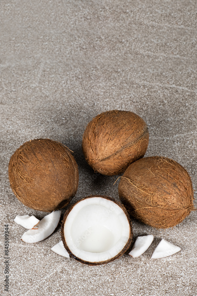 Whole coconuts and half a coconut on a blue and gray background close-up Whole coconuts and half a coconut on a blue and gray background close-up