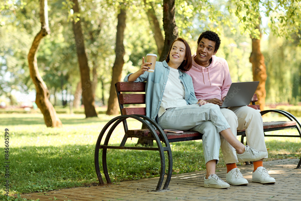 A diverse couple sitting on a park bench, working together on a laptop, surrounded by nature. A diverse couple sitting on a park bench, working together on a laptop, surrounded by nature.