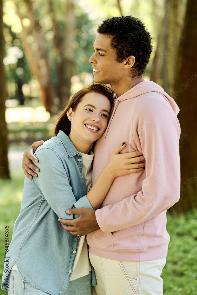 A man in vibrant attire tenderly embraces a woman in a park, showcasing a moment of intimacy and connection in a natural setting. A man in vibrant attire tenderly embraces a woman in a park, showcasing a moment of intimacy and connection in a natural setting.