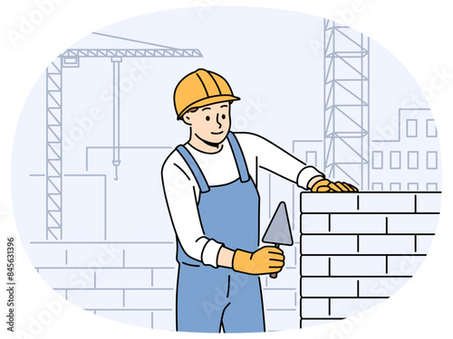 Positive male worker in uniform and helmet building house with bricks. Smiling man engineer busy laying blocks at construction site. Vector illustration.