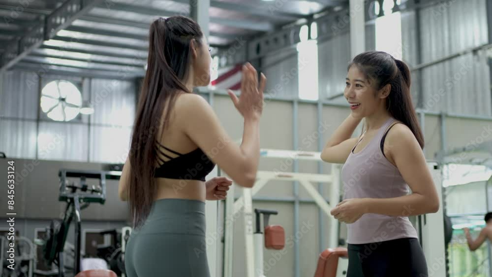 Portrait of a fit happy asian woman giving high five to her coach in a gym. Gym workout. Fitness trainer. Portrait of a fit happy asian woman giving high five to her coach in a gym. Gym workout. Fitness trainer.