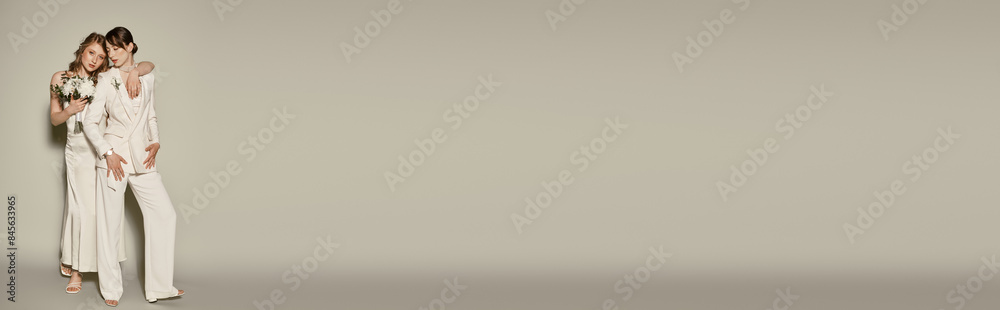 A lesbian couple in white wedding attire embraces on a grey background, celebrating their love. A lesbian couple in white wedding attire embraces on a grey background, celebrating their love.