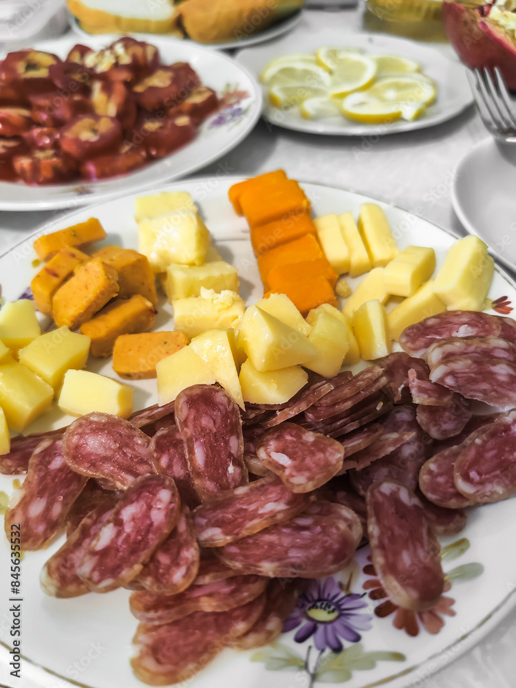 Simple feed featuring a plate adorned with several types of cheese and cured sausage cut into small pieces, offering variety of flavors. Close-up. Simple feed featuring a plate adorned with several types of cheese and cured sausage cut into small pieces, offering variety of flavors. Close-up.