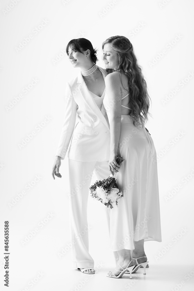 Two beautiful brides, dressed in white, share a happy moment during their wedding celebration. Two beautiful brides, dressed in white, share a happy moment during their wedding celebration.