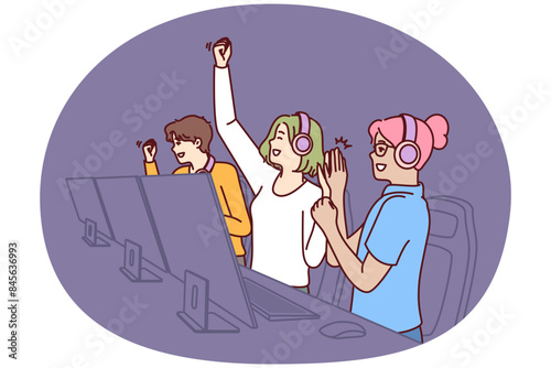 Team of delighted esports players participating in gamer competition in online multiplayer game or MMORPG. Teenage boys and girls sit at table with computers and celebrate victory in tournament