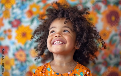 Portrait of a Young Girl With Curly Hair Laughing in Front of a Colorful Back...