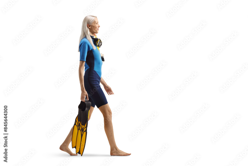 Full length profile shot of a woman in a diving suit carrying fins and walking Full length profile shot of a woman in a diving suit carrying fins and walking