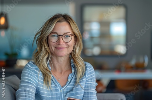 Smiling Woman Wearing Glasses and Blue Striped Shirt Sitting on a Couch Indoors