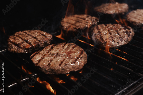 hamburgers cooking on the grill with open flame