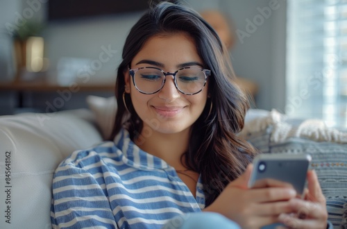 Smiling Woman Wearing Glasses and Blue Striped Shirt Sitting on a Couch Indoors