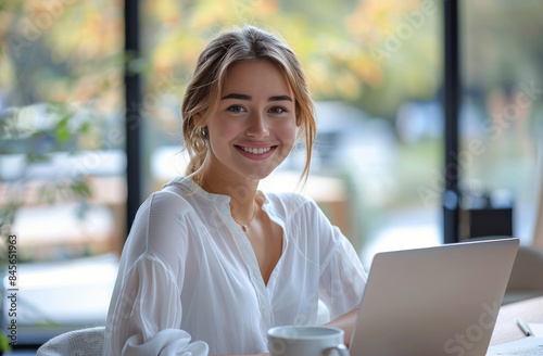 Smiling Woman Working on Laptop in Modern Cafe