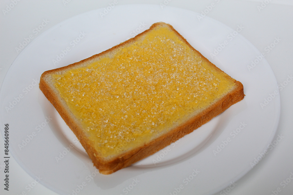 One slice of white square bread, with margarine spread and white crystal sugar topping, isolated on white background One slice of white square bread, with margarine spread and white crystal sugar topping, isolated on white background