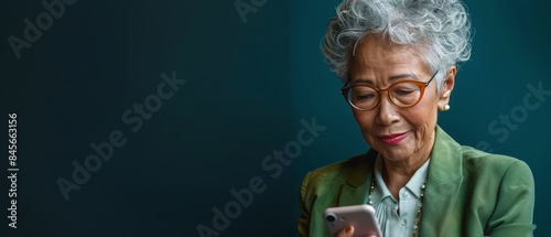 Senior Woman Using Smartphone In Front Of Green Chalkboard