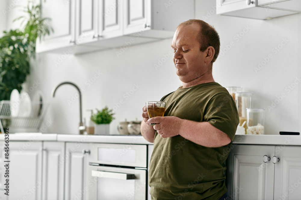 A man with inclusivity stands in his kitchen, casually dressed, holding a glass of liquid, taking a moment to relax and enjoy a peaceful moment. A man with inclusivity stands in his kitchen, casually dressed, holding a glass of liquid, taking a moment to relax and enjoy a peaceful moment.
